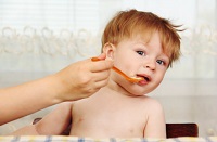 Toddler resisting being fed with a spoon